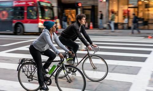 two people biking in LA with bus in background